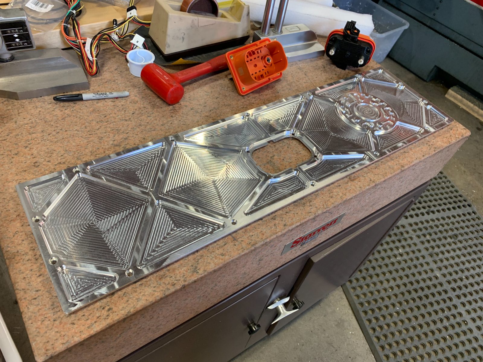 Completed CNC-machined decorative battery faceplate - large aluminum panel with intricate diamond and spiral pattern, fresh off the machine